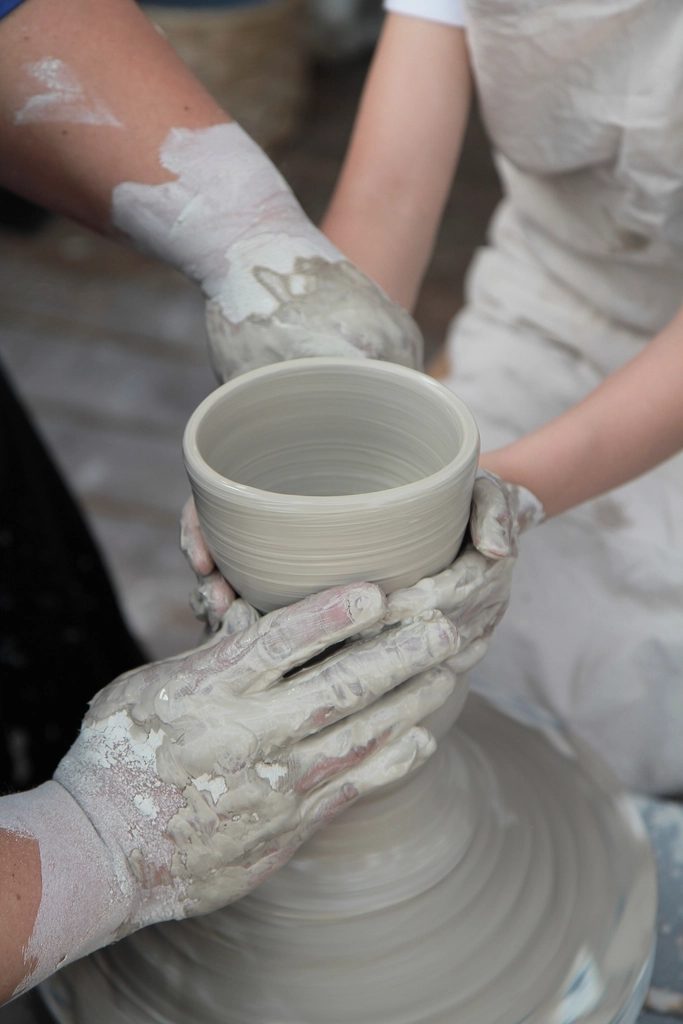 Hands shaping a mug on a potter's wheel