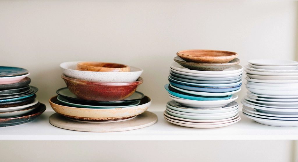 Stacks of glazed plates and bowls on a studio shelf
